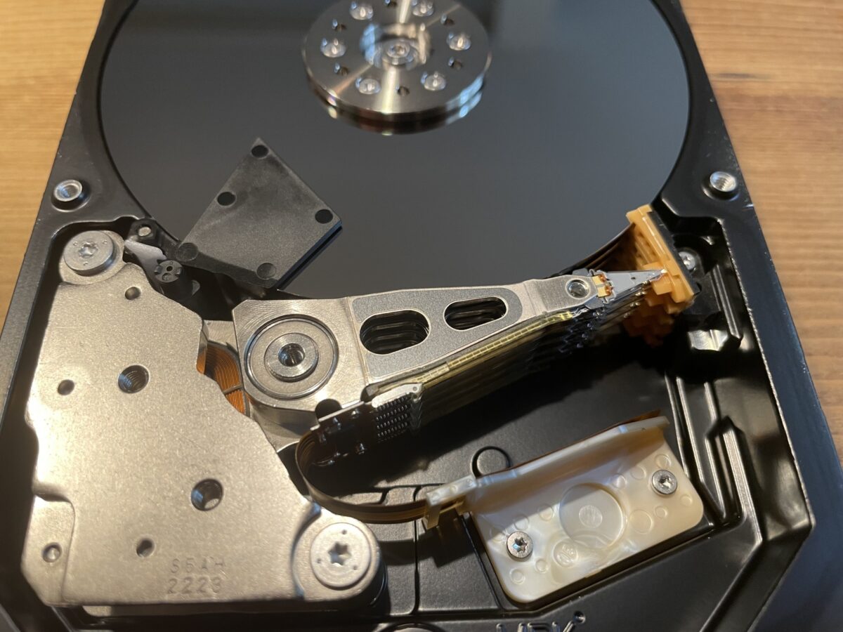 ハードディスクドライブ（HDD）の内部構造。プラッタ、ヘッドアーム、ボイスコイルモーター（VCM）が写っている。磁性管理が性能に影響する精密機器の一例。